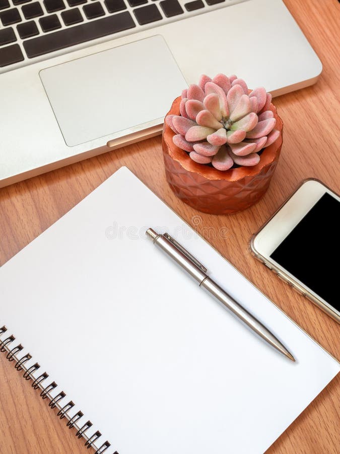 Caderno vazio com smartphone, laptop e a planta suculento no potenciômetro de cobre no fundo de madeira da tabela imagem de stock Caderno vazio com smartphone, laptop e a planta suculento no potenciômetro de cobre no fundo de madeira da tabela imagem de stock