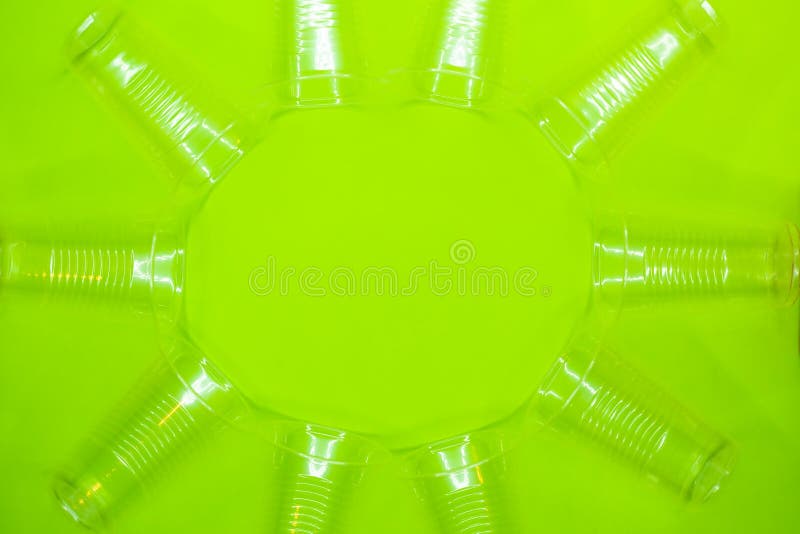 Cadre rond des tasses jetables en plastique trasparent sur le fond vert L'espace vide au centre de l'image image libre de droits Cadre rond des tasses jetables en plastique trasparent sur le fond vert L'espace vide au centre de l'image image libre de droits