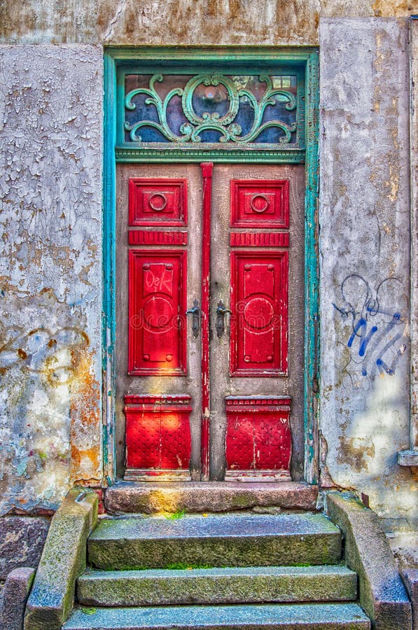 An old red door in a green doorway both of which have seen better days. An old red door in a green doorway both of which have seen better days.