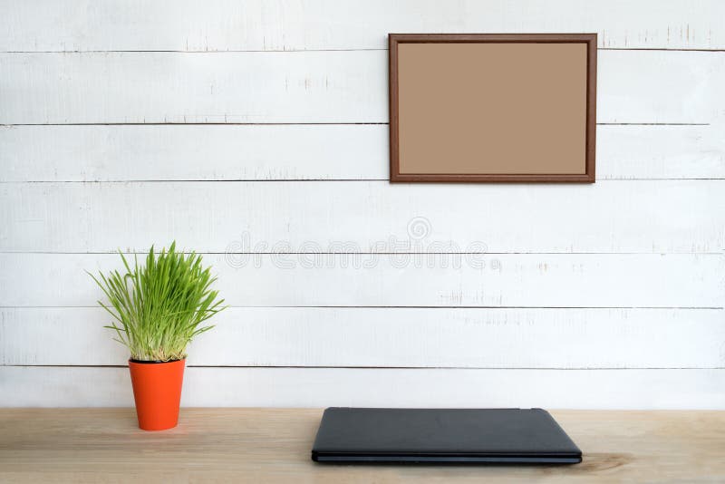 Cadre vide sur mur blanc Ordinateur portable fermé et installation de ménage verte Lieu de travail à domicile Placer le texte images stock Cadre vide sur mur blanc Ordinateur portable fermé et installation de ménage verte Lieu de travail à domicile Placer le texte images stock