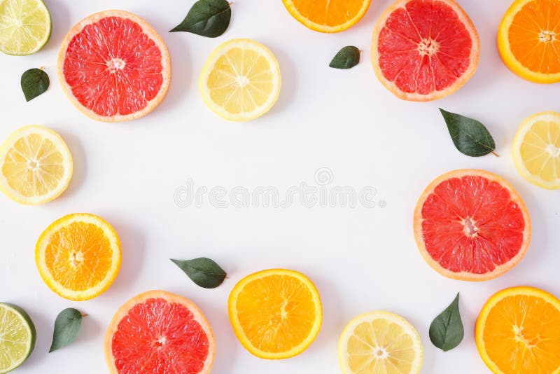 Cadrul colorat al fructelor din feliile de citrice și lasă o vedere de sus pe fond alb stock images