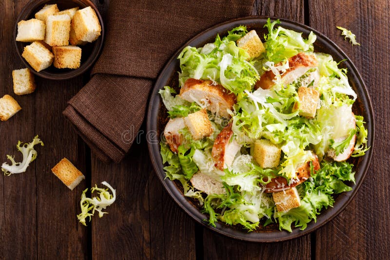 Caesar salad with grilled chicken meat, fresh lettuce, parmesan cheese and fried croutons. Classic North American cuisine. Top view stock photo