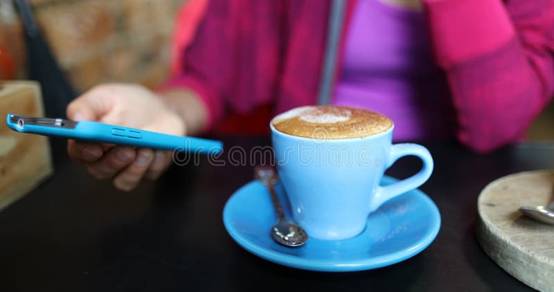 Cafeeira bebendo café cappuccino usando aplicativo de celular