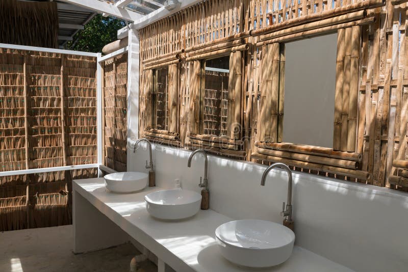 Cafe toilet of washbasin, mirror, wall made by bamboo wood with natural light. Tropical beach cafes. Cafe toilet of washbasin, mirror, wall made by bamboo wood with natural light. Tropical beach cafes