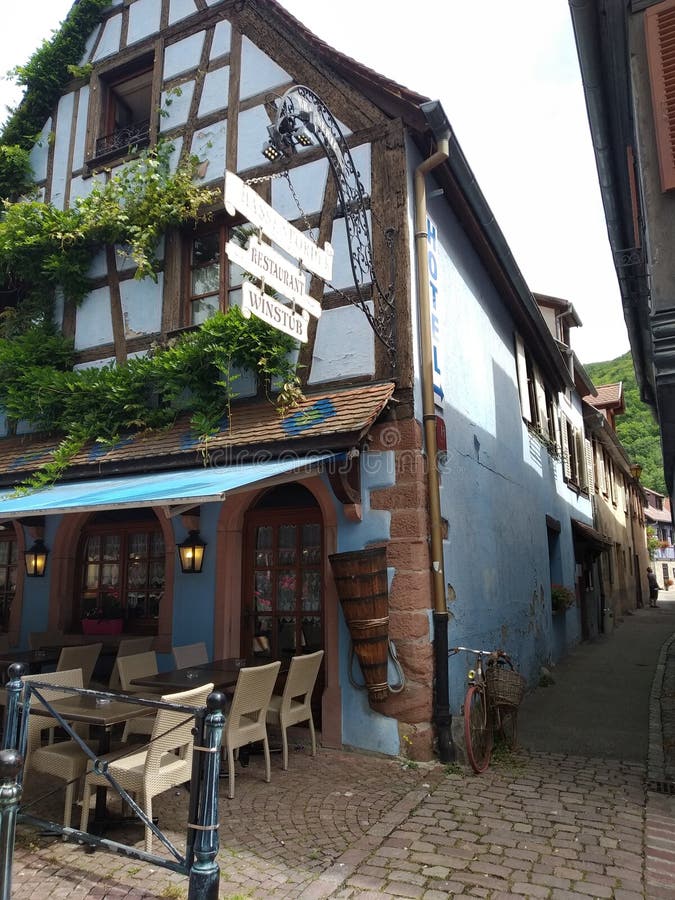 Caffetteria accogliente in una casa blu tipica nello stile renano in Kaysesberg, Alsacia fotografia stock libera da diritti Caffetteria accogliente in una casa blu tipica nello stile renano in Kaysesberg, Alsacia fotografia stock libera da diritti
