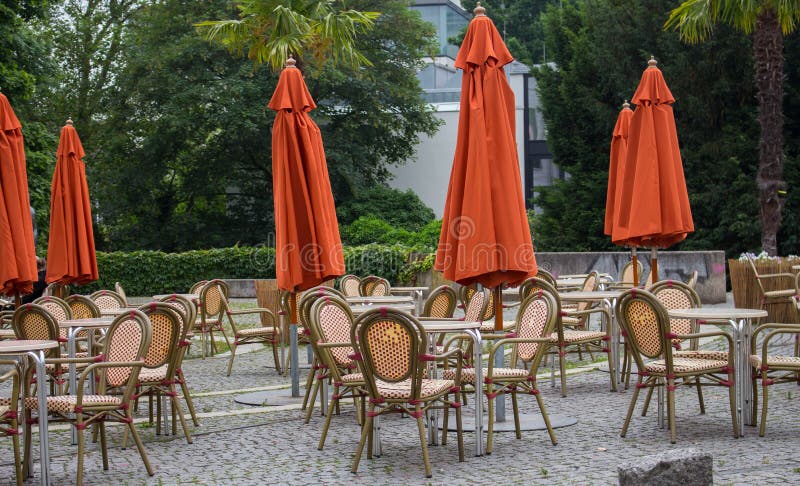 Caffè all'aperto vuoto con gli ombrelli chiusi Caffè della via con le tavole e le sedie vuote Concetto della mobilia del ristoran fotografie stock Caffè all'aperto vuoto con gli ombrelli chiusi Caffè della via con le tavole e le sedie vuote Concetto della mobilia del ristoran fotografie stock