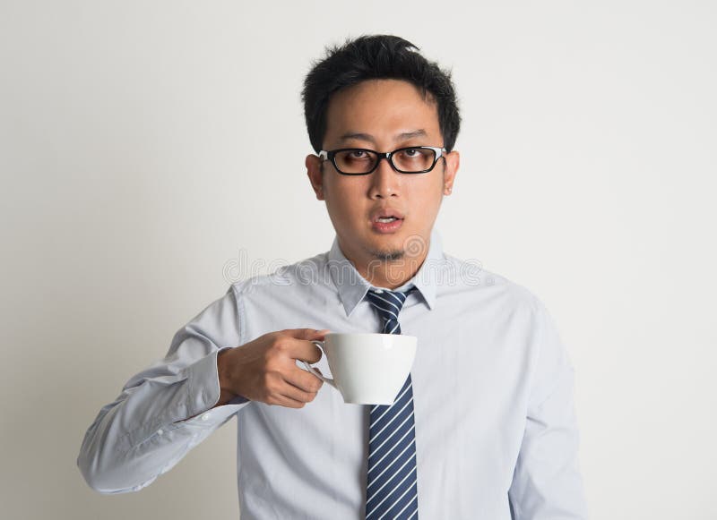 Caffè asiatico stanco della bevanda dell'uomo d'affari fotografia stock Caffè asiatico stanco della bevanda dell'uomo d'affari fotografia stock