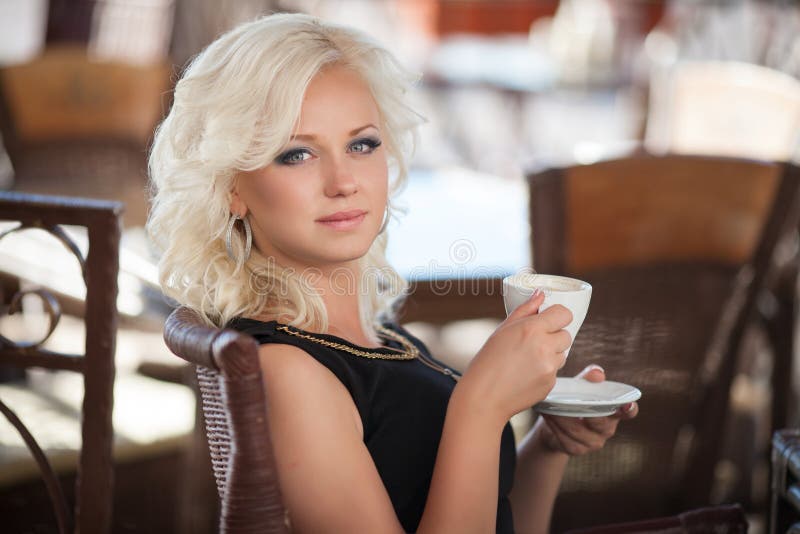 Caffè bevente della bella donna nel ristorante del caffè, ragazza nella barra, vacanze estive. Abbastanza biondo alla prima colazi fotografia stock libera da diritti Caffè bevente della bella donna nel ristorante del caffè, ragazza nella barra, vacanze estive. Abbastanza biondo alla prima colazi fotografia stock libera da diritti