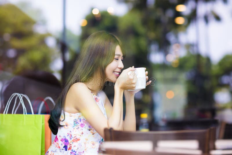 Caffè bevente sorridente della giovane donna nel negozio del caffè fotografia stock Caffè bevente sorridente della giovane donna nel negozio del caffè fotografia stock