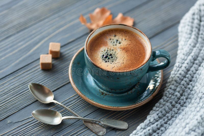 Caffè blu del whith della tazza, maglione tricottato, foglie di autunno su fondo di legno immagini stock Caffè blu del whith della tazza, maglione tricottato, foglie di autunno su fondo di legno immagini stock