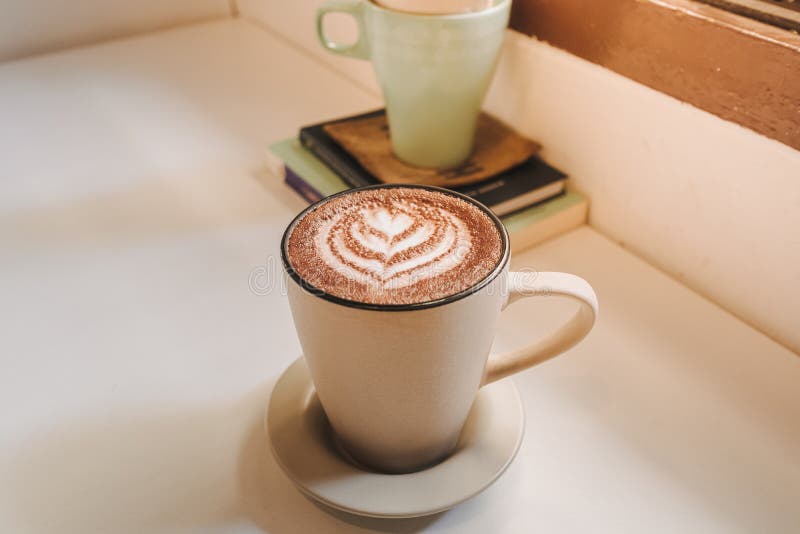 Caffè caldo servito in una tazza bianca sul tavolo al mattino. Caffé di latte caldo servito in una tazza bianca sul tavolo al mattino caldo.