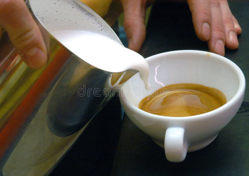 View of fresh milk stream flowing in to the cup of coffee. View of fresh milk stream flowing in to the cup of coffee