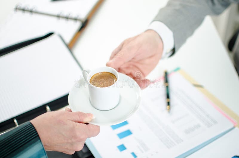 Assistente che offre il caffè al suo capo fotografia stock