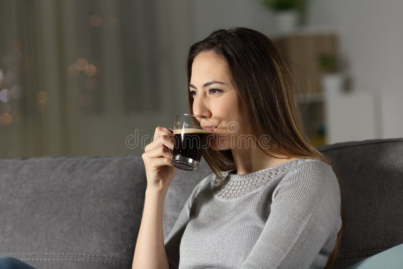Caffè decaffeinato bevente della donna rilassata nella notte fotografia stock libera da diritti Caffè decaffeinato bevente della donna rilassata nella notte fotografia stock libera da diritti