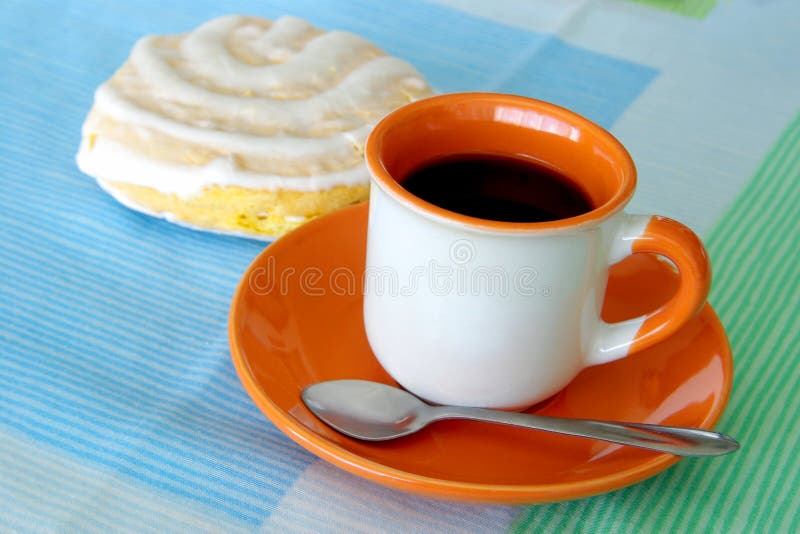 Cup of coffee and a cookie over a colorful table cover. Cup of coffee and a cookie over a colorful table cover