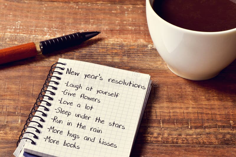 Caffè e blocco note con una lista delle risoluzioni dei nuovi anni
