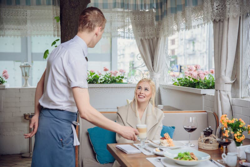 Caffè espresso o cappuccino d'ordinazione del cliente della donna al contatore della barra in ristorante immagini stock Caffè espresso o cappuccino d'ordinazione del cliente della donna al contatore della barra in ristorante immagini stock