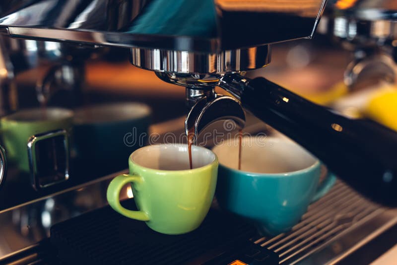 Caffè espresso preparante a macchina del caffè e versare nelle tazze colorate