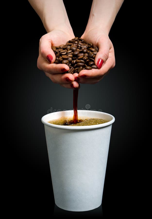 Coffee flows from a handful of beans into a paper cup. Coffee flows from a handful of beans into a paper cup