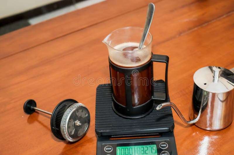 Caffè nero fresco in una pressa francese di vetro e cucchiaio in scala con bollitore di manzo inossidabile immagini stock libere da diritti