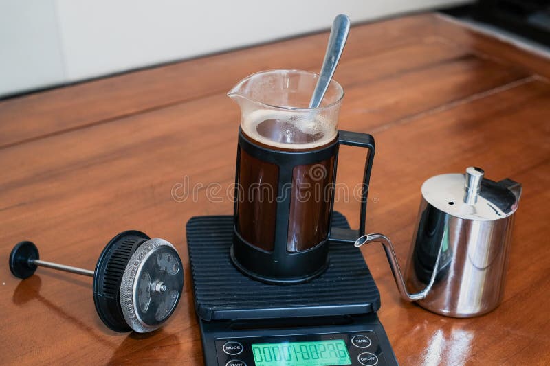 Caffè nero fresco in una pressa francese di vetro e cucchiaio in scala con bollitore di manzo inossidabile immagini stock