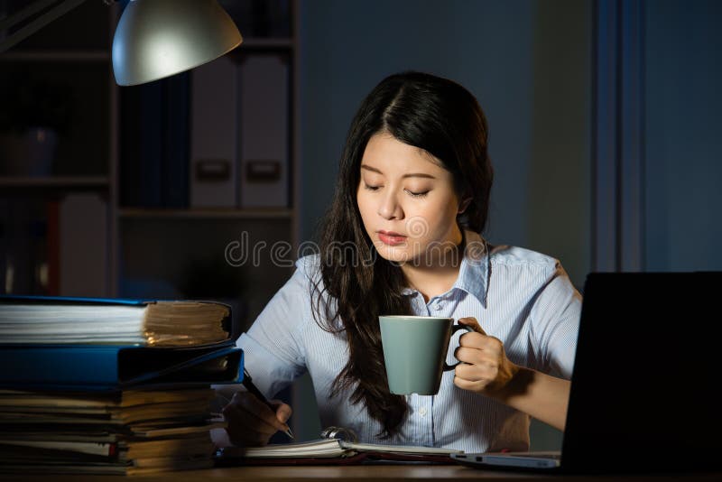 Café asiático da bebida da mulher de negócio que trabalha fora do tempo estipulado tardio fotografia de stock Café asiático da bebida da mulher de negócio que trabalha fora do tempo estipulado tardio fotografia de stock