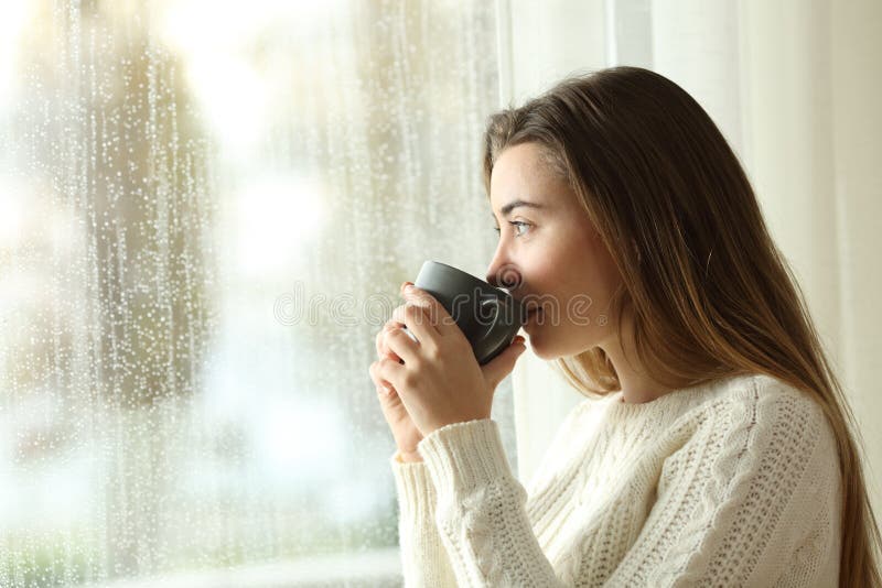 Café bebendo adolescente que olha através de uma janela um o dia chuvoso imagens de stock Café bebendo adolescente que olha através de uma janela um o dia chuvoso imagens de stock