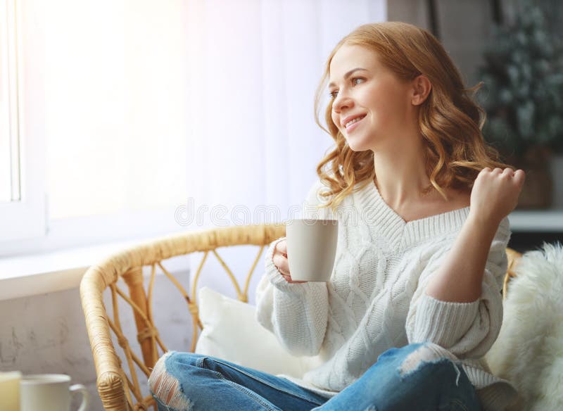 Café bebendo da manhã da jovem mulher feliz pela janela no inverno