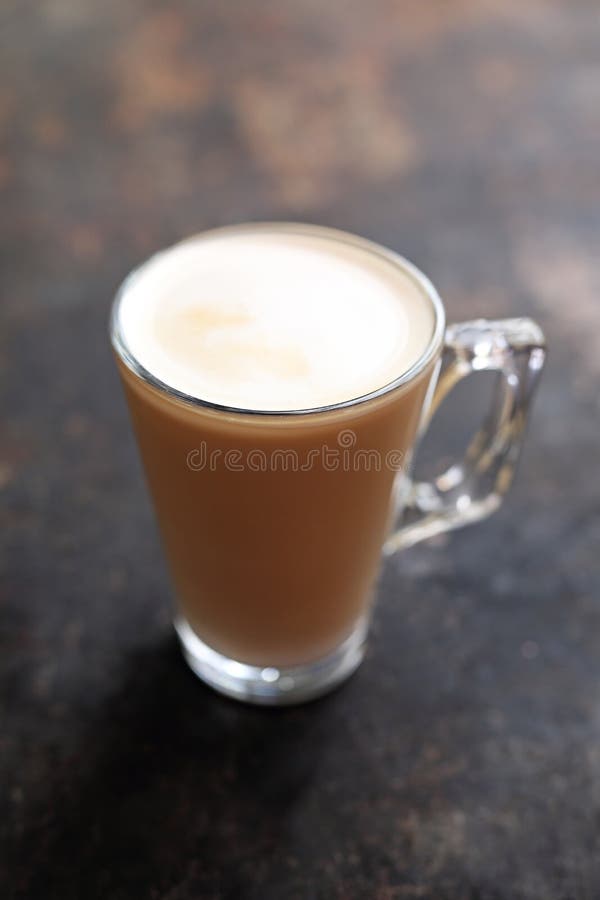 Café blanc plat avec la tasse en verre transparente de mousse de lait photos stock Café blanc plat avec la tasse en verre transparente de mousse de lait photos stock