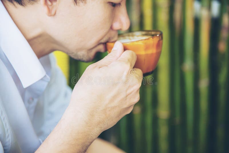 Café chaud de boissons asiatiques occasionnelles d'homme heureusement en nature photo libre de droits Café chaud de boissons asiatiques occasionnelles d'homme heureusement en nature photo libre de droits