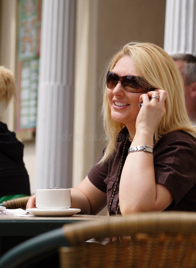 Attractive lady having coffee at a cafe, taking a call on her mobile phone. Attractive lady having coffee at a cafe, taking a call on her mobile phone.