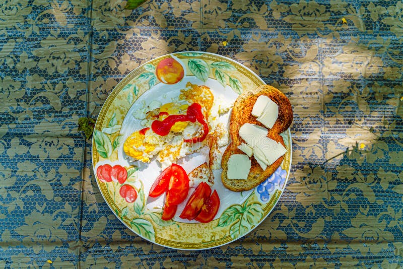 Café da manhã completo - ovos fritos, ketchup, tomate cortado, fatia brindada do pão branco com fatias de manteiga em uma placa b fotografia de stock Café da manhã completo - ovos fritos, ketchup, tomate cortado, fatia brindada do pão branco com fatias de manteiga em uma placa b fotografia de stock
