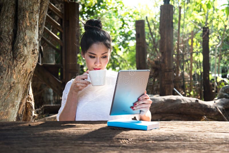 Relaxation woman drink coffee and reading laptop in the park. Relaxation woman drink coffee and reading laptop in the park