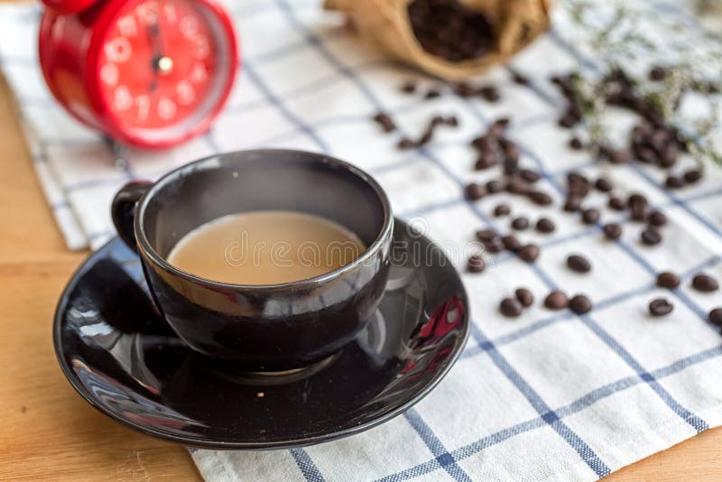 Caf? em um copo de caf? preto colocado em uma tela com feij?es de caf? e despertadores da manh? fotografia de stock royalty free Caf? em um copo de caf? preto colocado em uma tela com feij?es de caf? e despertadores da manh? fotografia de stock royalty free