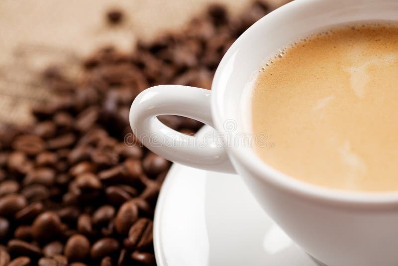 A Cup of Coffee with a Saucer and Coffee Beans in a macro image. A Cup of Coffee with a Saucer and Coffee Beans in a macro image