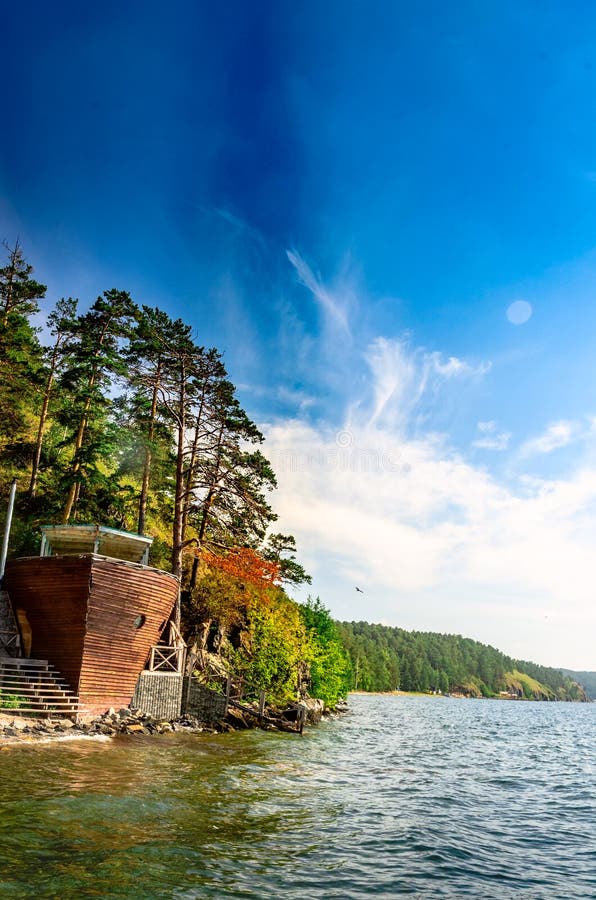 Café in Form eines Schiffskörpers an der Küste eines großen Bergsees lizenzfreie stockfotografie