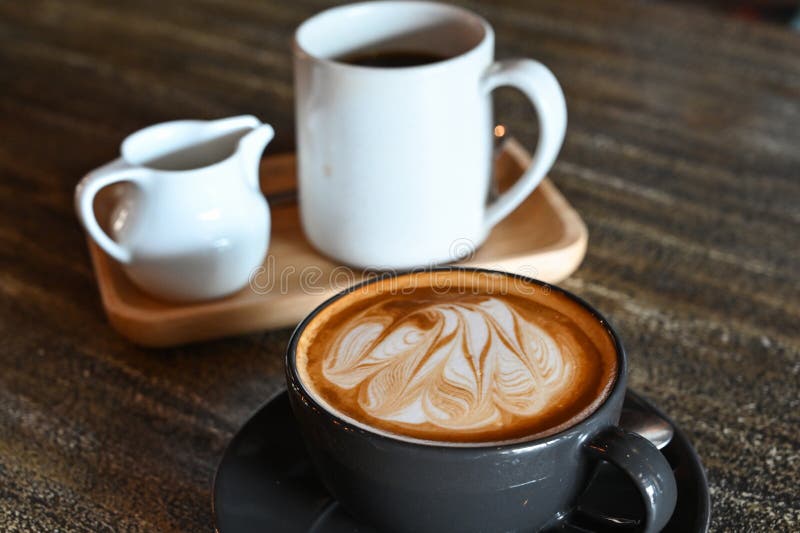 Café latte sur la table en bois sombre. Café de café dans une tasse noire sur la table en bois sombre