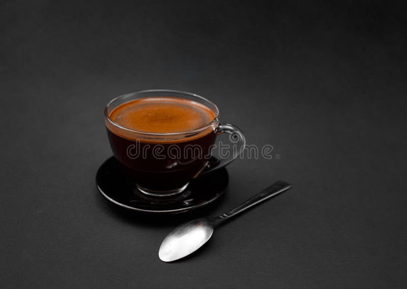 Café negro, natural, fragante en la taza transparente en un fondo negro Bebida caliente imagenes de archivo