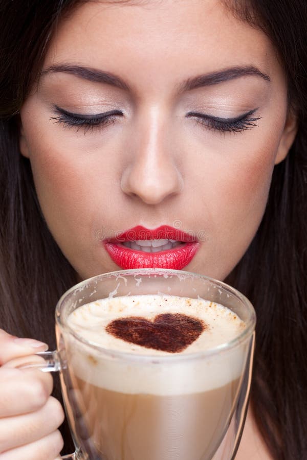 Woman drinking a cappuccino coffee with a love heart shape sprinking on top. Woman drinking a cappuccino coffee with a love heart shape sprinking on top.