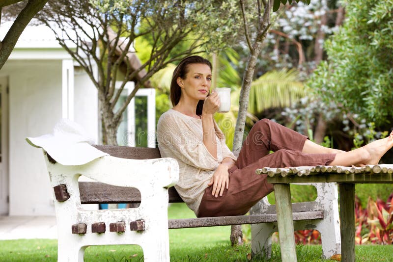 Café potable de femme dehors dans le jardin photographie stock libre de droits Café potable de femme dehors dans le jardin photographie stock libre de droits