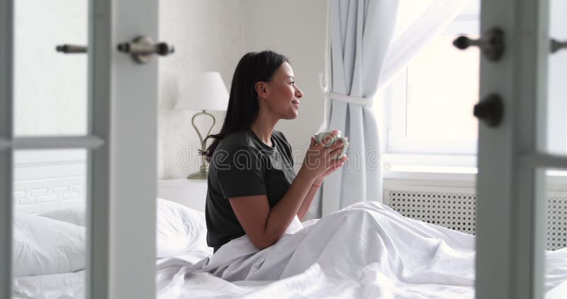 Café potable de femme heureuse afro-américaine au lit.