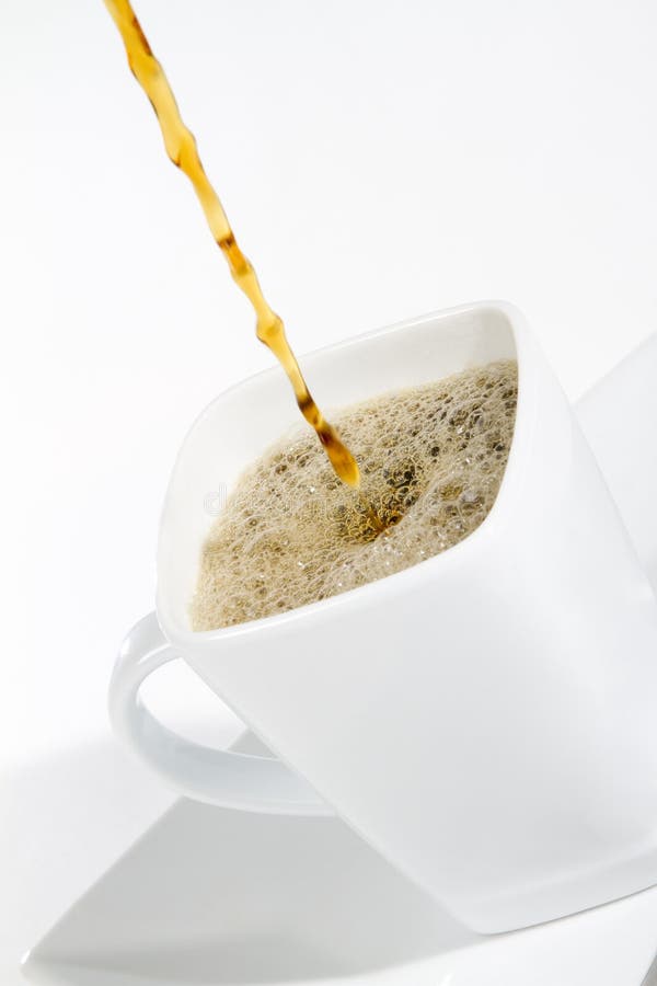 A stream of coffee pouring into a white coffee mug. shot on white. A stream of coffee pouring into a white coffee mug. shot on white