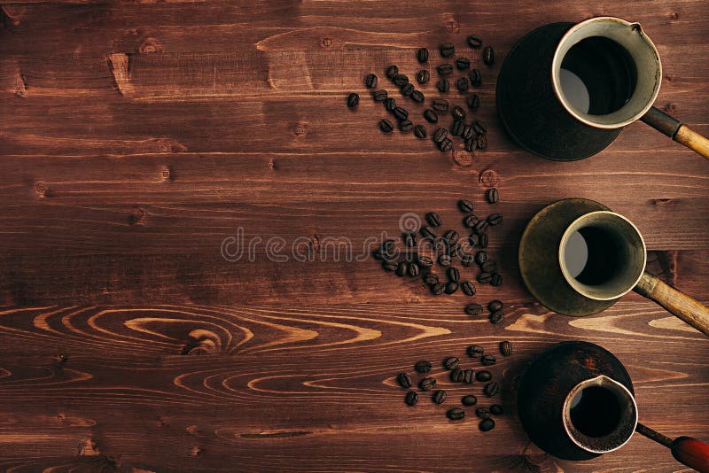 Café quente no cezve turco gasto amável diferente dos potenciômetros com espaço da cópia no fundo velho marrom da placa de madeir fotos de stock Café quente no cezve turco gasto amável diferente dos potenciômetros com espaço da cópia no fundo velho marrom da placa de madeir fotos de stock