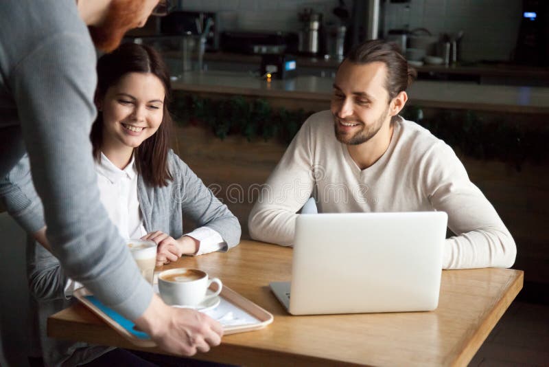 Café servant de serveur aux couples millénaires heureux en café photographie stock libre de droits Café servant de serveur aux couples millénaires heureux en café photographie stock libre de droits