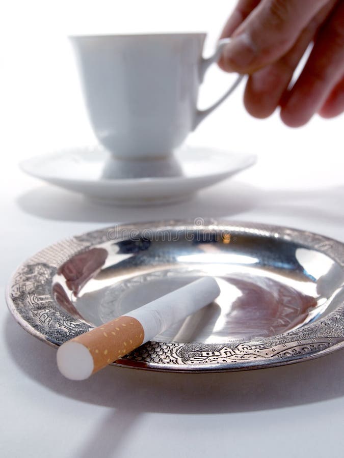 Color photo of a cup of coffee and a cigarette in an ashtray. Color photo of a cup of coffee and a cigarette in an ashtray