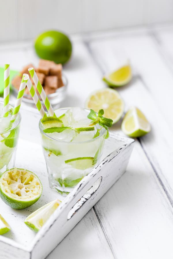 Caipirinha, cocktail do mojito com as folhas do cal, do açúcar mascavado, do gelo e de hortelã nos vidros bonitos, citrino verde imagens de stock Caipirinha, cocktail do mojito com as folhas do cal, do açúcar mascavado, do gelo e de hortelã nos vidros bonitos, citrino verde imagens de stock