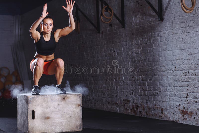 Caixa de salto da mulher Mulher da aptidão que faz o exercício do salto da caixa no gym apto da cruz imagem de stock Caixa de salto da mulher Mulher da aptidão que faz o exercício do salto da caixa no gym apto da cruz imagem de stock