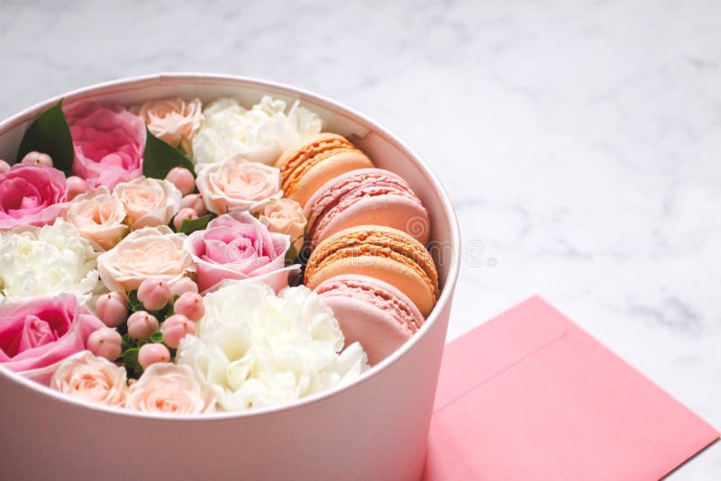 Caixa redonda do presente com flores, rosas e bolo da amêndoa dos bolinhos de amêndoa com o envelope cor-de-rosa na tabela imagens de stock Caixa redonda do presente com flores, rosas e bolo da amêndoa dos bolinhos de amêndoa com o envelope cor-de-rosa na tabela imagens de stock