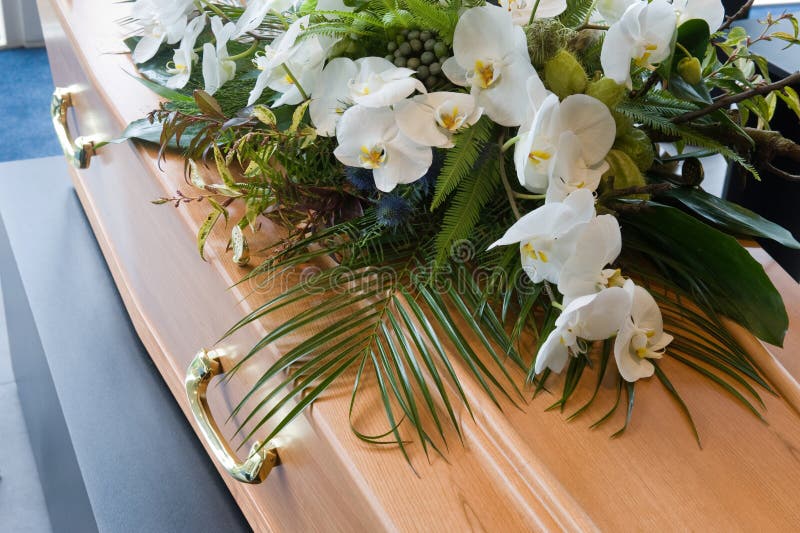A coffin with a flower arrangement in a morgue. A coffin with a flower arrangement in a morgue