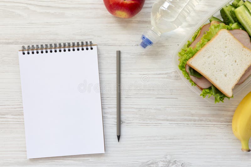 Caja de almuerzo escolar sana con el cuaderno y el lápiz en el woode blanco imágenes de archivo libres de regalías Caja de almuerzo escolar sana con el cuaderno y el lápiz en el woode blanco imágenes de archivo libres de regalías